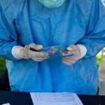 Profissional de saúde examina uma amostra de sangue durante uma ação de atendimento.