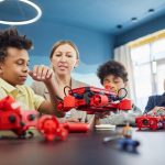 Estudantes e uma professora colaboram na construção de um projeto de robótica em uma sala de aula.