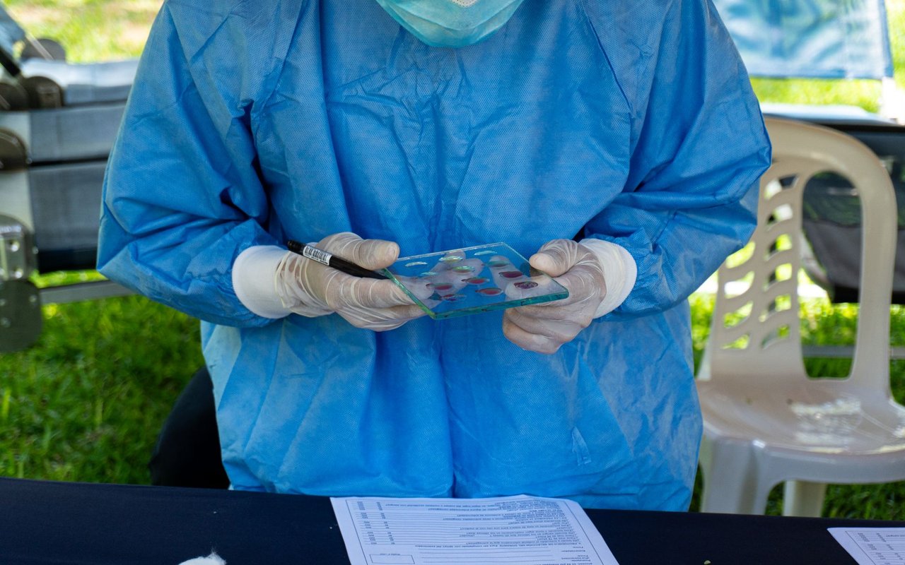 Profissional de saúde examina uma amostra de sangue durante uma ação de atendimento.