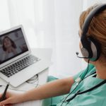 Profissional de saúde realiza uma consulta remota com um paciente por meio de um laptop.