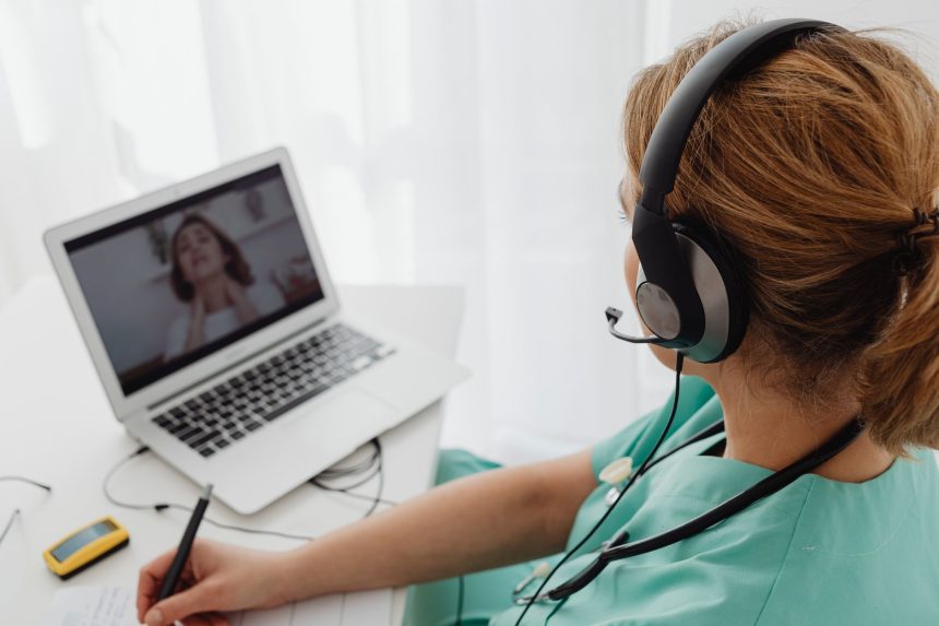 Profissional de saúde realiza uma consulta remota com um paciente por meio de um laptop.